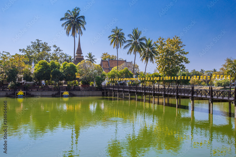 Background of Wat Traphang Thong, which is located in the middle of the water and has a wooden bridge, which is used to organize ceremonies (Loi Krathong, New Year) in Sukhothai province, Thailand. Background of Wat Traphang Thong, which is located in the middle of the water and has a wooden bridge, which is used to organize ceremonies (Loi Krathong, New Year) in Sukhothai province, Thailand.