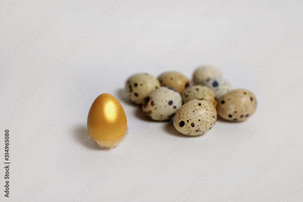 Golden quail egg with ordinary eggs on a white background, quail eggs around one golden one, Easter concept or motivation for improvement, a call for special