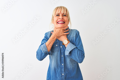 Middle age woman wearing casual denim shirt standing over isolated white background shouting and suffocate because painful strangle. Health problem. Asphyxiate and suicide concept.