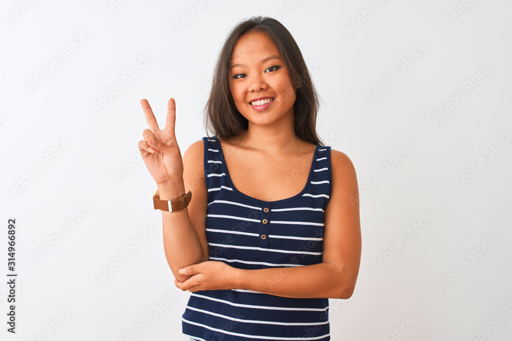 Young chinese woman wearing striped t-shirt standing over isolated white background smiling with happy face winking at the camera doing victory sign. Number two. Young chinese woman wearing striped t-shirt standing over isolated white background smiling with happy face winking at the camera doing victory sign. Number two.
