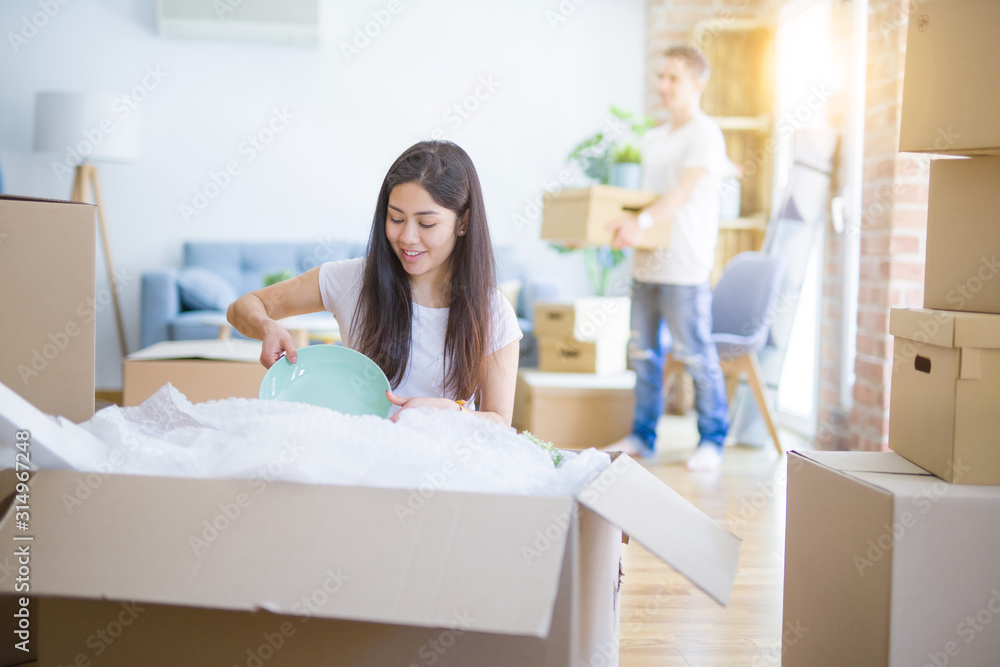 Young beautiful couple open cardboard boxes to order new home Young beautiful couple open cardboard boxes to order new home