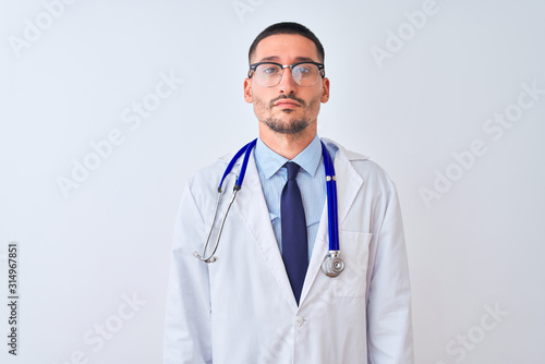 Young doctor man wearing stethoscope over isolated background Relaxed with serious expression on face. Simple and natural looking at the camera. © Krakenimages.com