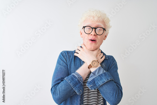 Young albino blond man wearing denim shirt and glasses over isolated white background shouting suffocate because painful strangle. Health problem. Asphyxiate and suicide concept.