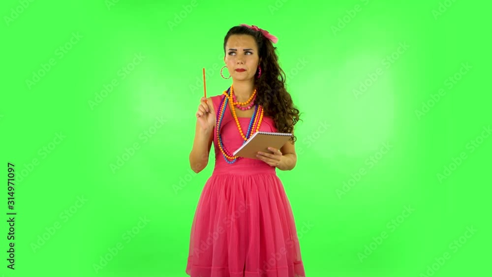 Girl stands and thinks, then writes with pencil in notebook and gets angry. Green screen Girl stands and thinks, then writes with pencil in notebook and gets angry. Green screen