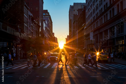 Crowds of diverse people walk across a busy intersection on 5th Avenue in New York City with sunlight background © deberarr