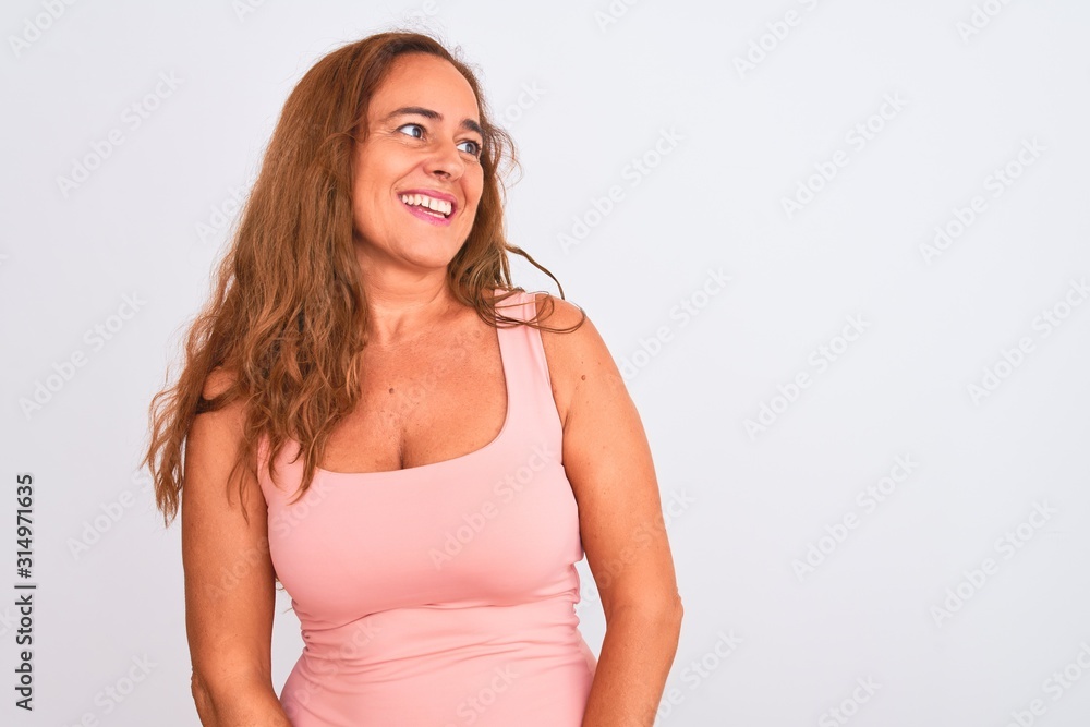 Middle age mature woman standing over white isolated background looking away to side with smile on face, natural expression. Laughing confident. Middle age mature woman standing over white isolated background looking away to side with smile on face, natural expression. Laughing confident.