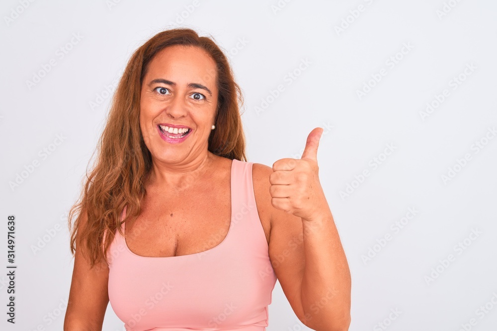 Middle age mature woman standing over white isolated background happy with big smile doing ok sign, thumb up with fingers, excellent sign Middle age mature woman standing over white isolated background happy with big smile doing ok sign, thumb up with fingers, excellent sign