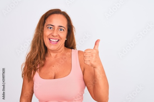 Wallpaper Mural Middle age mature woman standing over white isolated background happy with big smile doing ok sign, thumb up with fingers, excellent sign Torontodigital.ca