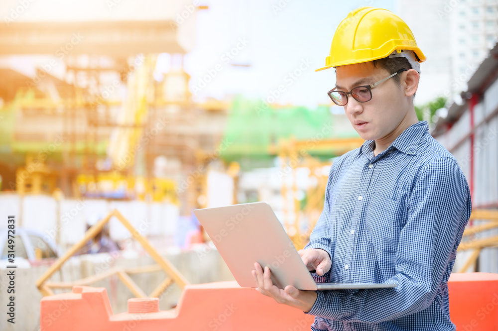 Young asian engineers are working on the construction site. Wear a yellow helmet safety. Hand holding computer laptop Young asian engineers are working on the construction site. Wear a yellow helmet safety. Hand holding computer laptop