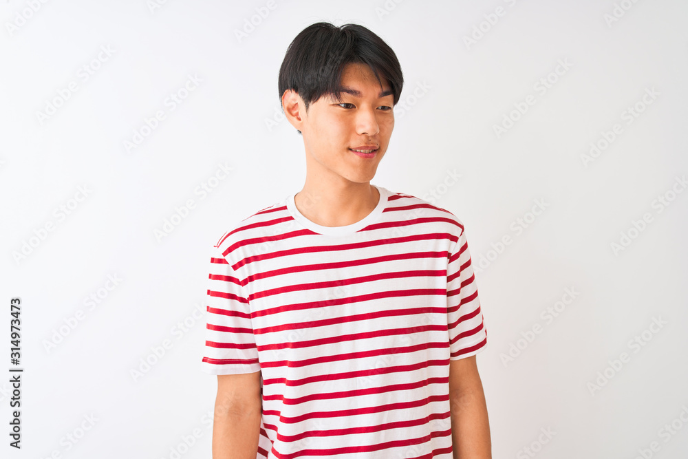 Young chinese man wearing casual striped t-shirt standing over isolated white background looking away to side with smile on face, natural expression. Laughing confident. Young chinese man wearing casual striped t-shirt standing over isolated white background looking away to side with smile on face, natural expression. Laughing confident.