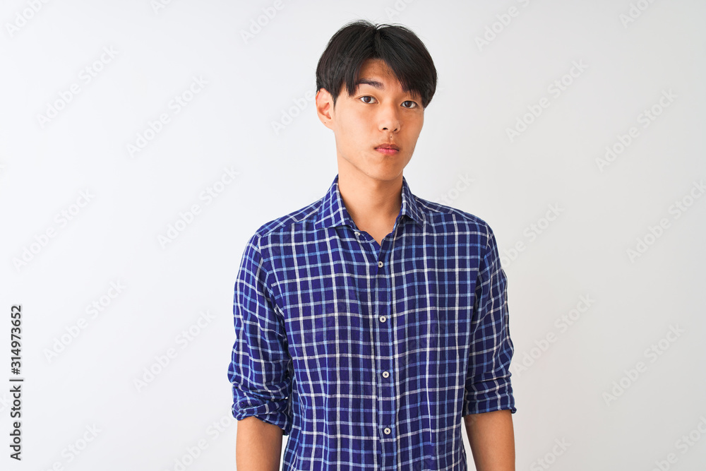 Young chinese man wearing casual blue shirt standing over isolated white background Relaxed with serious expression on face. Simple and natural looking at the camera. Young chinese man wearing casual blue shirt standing over isolated white background Relaxed with serious expression on face. Simple and natural looking at the camera.
