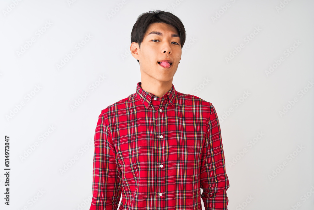 Young chinese man wearing casual red shirt standing over isolated white background sticking tongue out happy with funny expression. Emotion concept. Young chinese man wearing casual red shirt standing over isolated white background sticking tongue out happy with funny expression. Emotion concept.