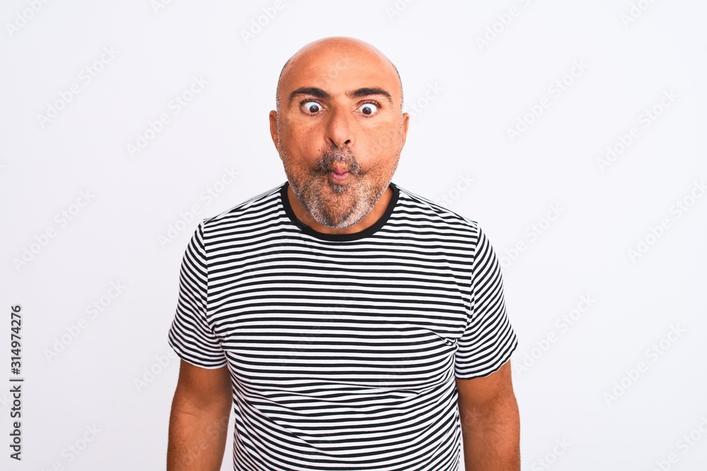 Middle age handsome man wearing striped navy t-shirt over isolated white background making fish face with lips, crazy and comical gesture. Funny expression. Middle age handsome man wearing striped navy t-shirt over isolated white background making fish face with lips, crazy and comical gesture. Funny expression.