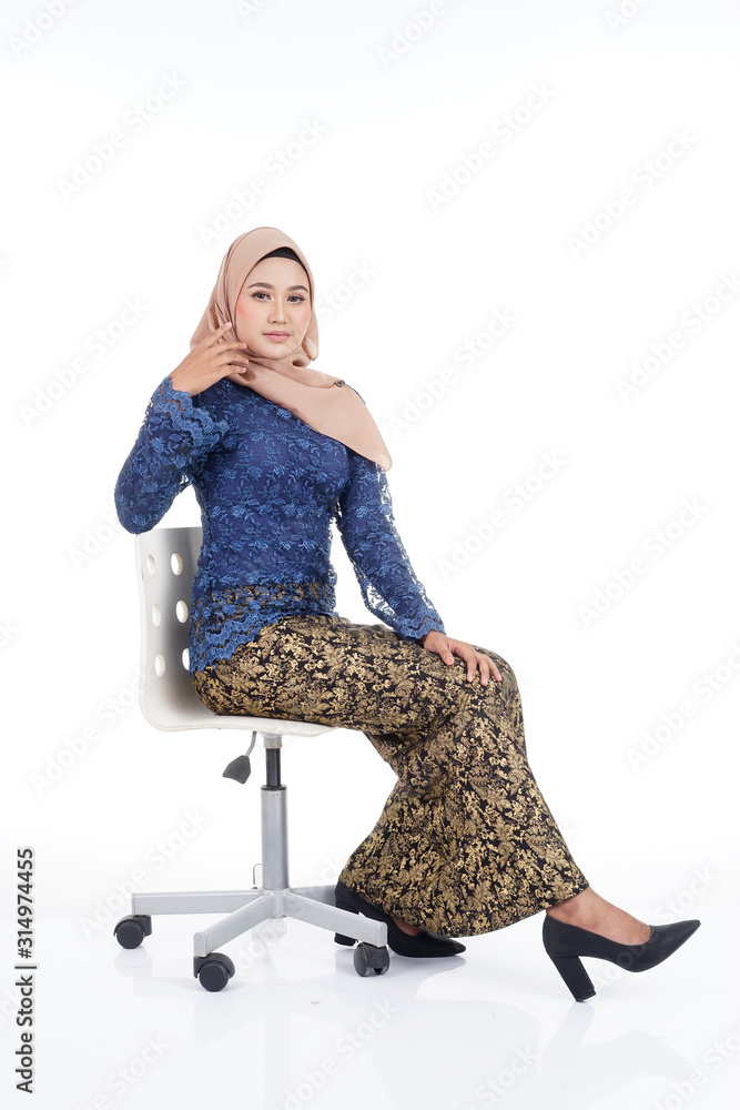 Fototapeta premium Attractive female model wearing dark blue modern kurung with hijab, a modern urban lifestyle apparel for Muslim women isolated on white background. Beauty and hijab fashion concept.