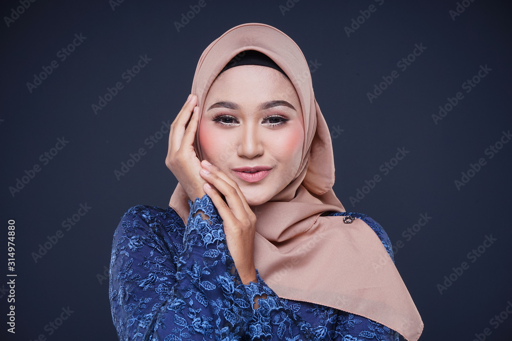 Closeup of a beautiful female Muslim model wearing dark blue modern kurung with hijab, a modern urban lifestyle apparel for Muslim women isolated on grey background. Beauty and hijab fashion concept. Closeup of a beautiful female Muslim model wearing dark blue modern kurung with hijab, a modern urban lifestyle apparel for Muslim women isolated on grey background. Beauty and hijab fashion concept.
