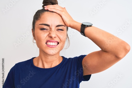 Foto Young beautiful woman wearing blue casual t-shirt standing over isolated white background stressed with hand on head, shocked with shame and surprise face, angry and frustrated