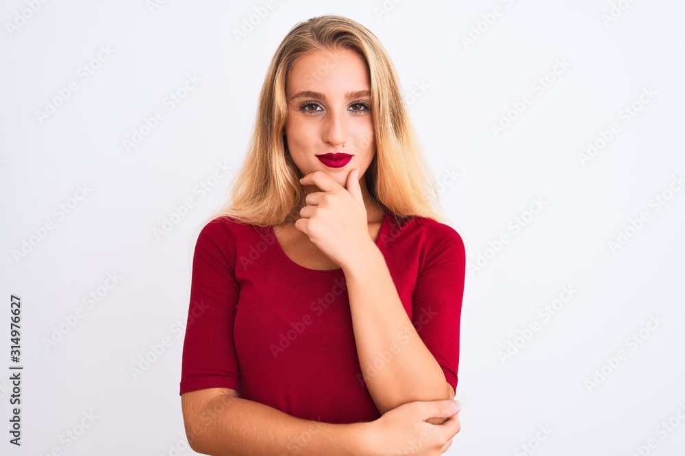 Young beautiful woman wearing red t-shirt standing over isolated white background looking confident at the camera with smile with crossed arms and hand raised on chin. Thinking positive. Young beautiful woman wearing red t-shirt standing over isolated white background looking confident at the camera with smile with crossed arms and hand raised on chin. Thinking positive.
