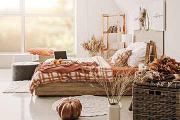 Stylish interior of room with big comfortable bed and autumn decor
