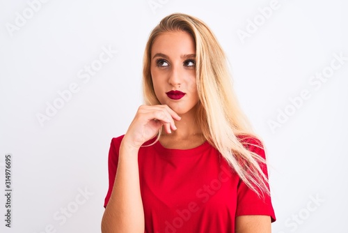 Young beautiful woman wearing red casual t-shirt standing over isolated white background with hand on chin thinking about question, pensive expression. Smiling with thoughtful face. Doubt concept.