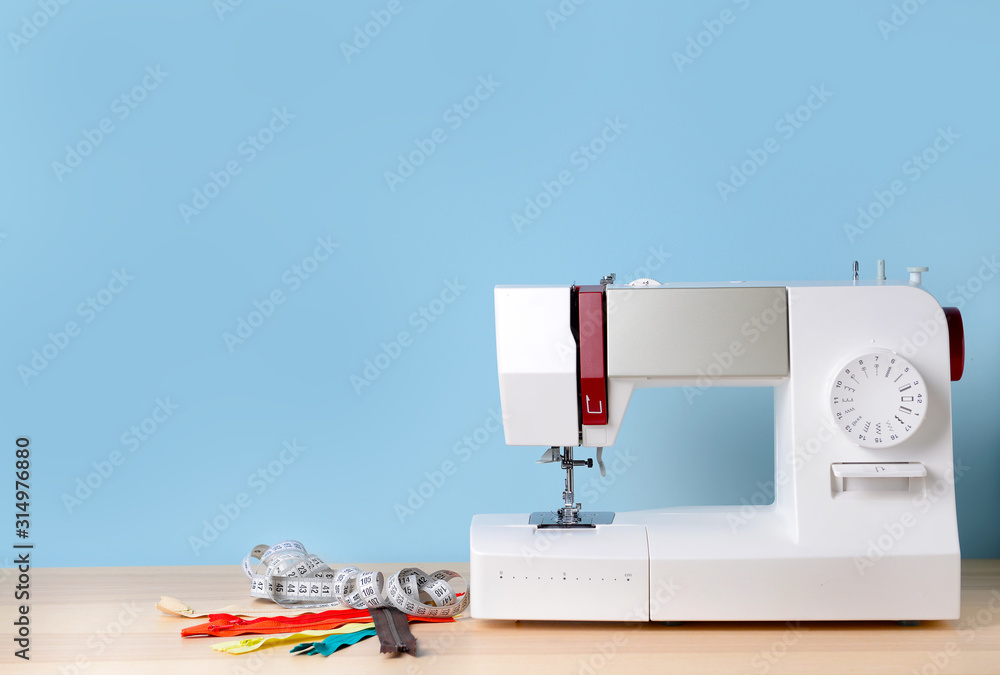 Sewing machine with supplies on table - obrazy, fototapety, plakaty 