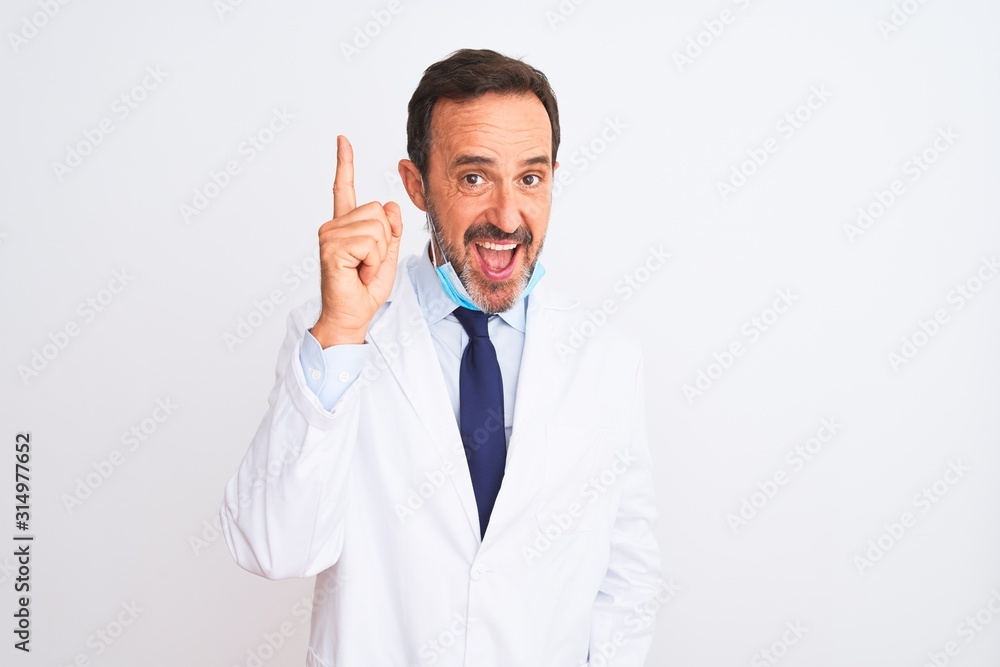 Middle age scientist man wearing coat and medical mask over isolated white background pointing finger up with successful idea. Exited and happy. Number one. Middle age scientist man wearing coat and medical mask over isolated white background pointing finger up with successful idea. Exited and happy. Number one.