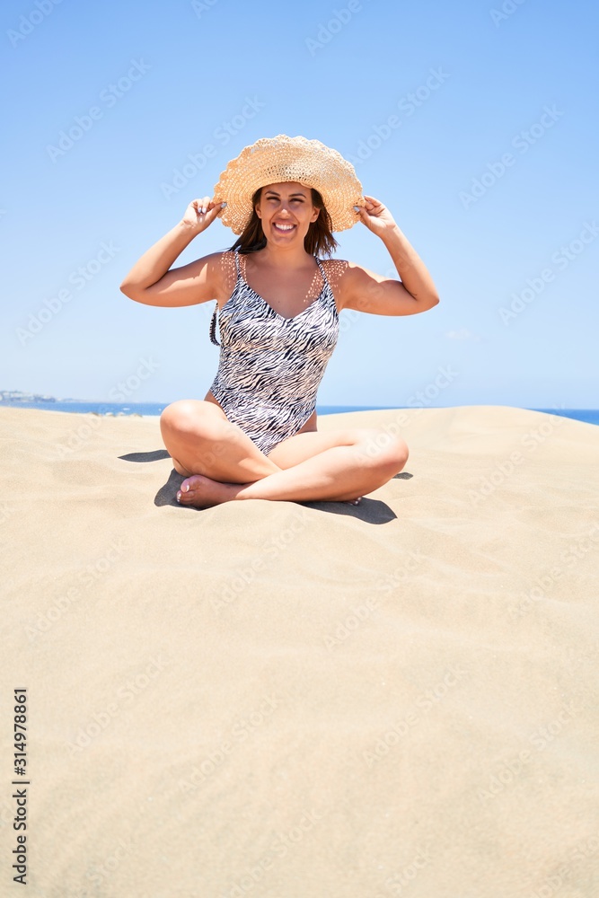 Young beautiful woman sunbathing sitting on the sand wearing summer swinsuit at maspalomas dunes bech Young beautiful woman sunbathing sitting on the sand wearing summer swinsuit at maspalomas dunes bech