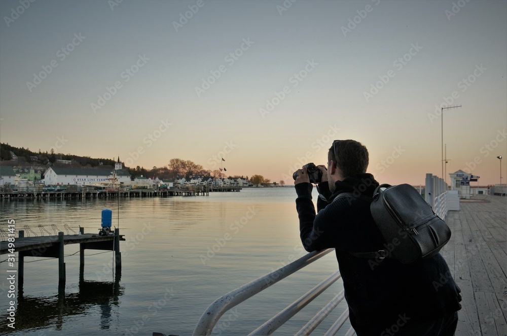 Obraz premium Man taking photos of sunset over lake