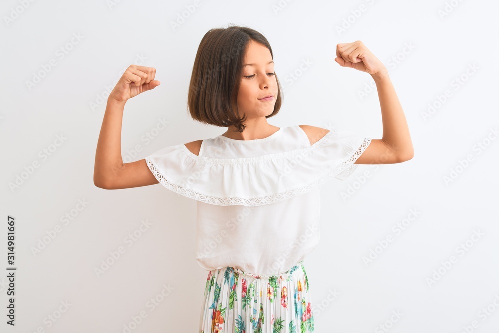 Young beautiful child girl wearing casual dress standing over isolated white background showing arms muscles smiling proud. Fitness concept. Young beautiful child girl wearing casual dress standing over isolated white background showing arms muscles smiling proud. Fitness concept.