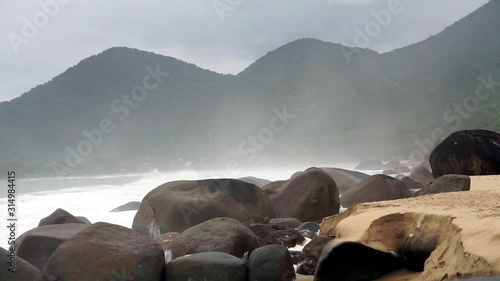 Ocean waves crashing on the giant rocks on Cepilho Beach in Trinidade, Brazil photo