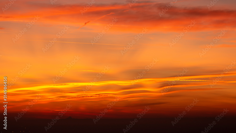 Obraz premium Bergamo, Italy. Fiery sunset over the Po valley and the Alps. Clouds that create light red and orange waves. Fabulous contest. Warm colors