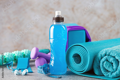 Drink isotonic bottle and fitness equipment on a grey background. Sport, fitness or yoga concept photo