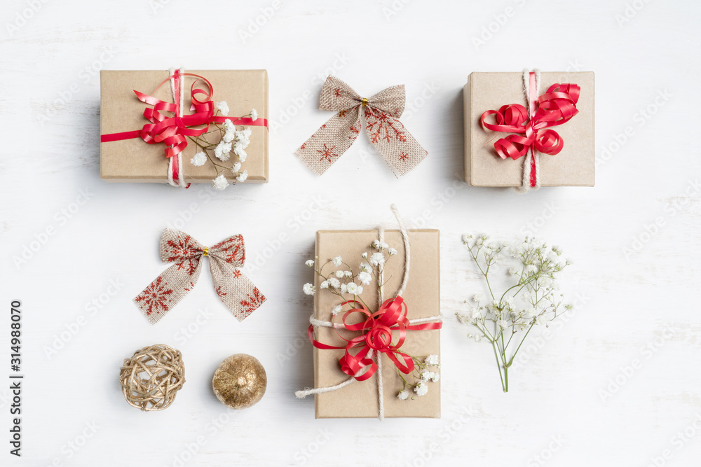 Christmas gifts with red ribbons, bows, gold pine cones and delicate white flowers on a rustic white background shot flat - lay. Christmas gifts with red ribbons, bows, gold pine cones and delicate white flowers on a rustic white background shot flat - lay.