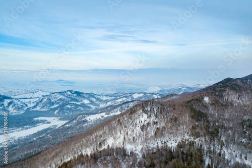 Picturesque landscape in the Altai mountains with snow-capped peaks under a blue sky with clouds in winter. White snow and calm.