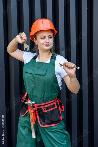 Attractive woman in coverall with tools posing on abstract background