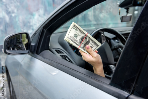 Female hands offer dolar bundle. Woman driver giving bribe