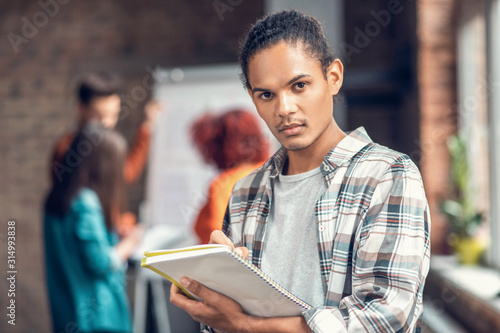 Handsome dark-eyed student feeling concentrated while studying