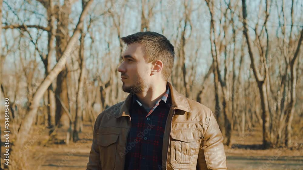Portrait of a guy in a leather jacket on a background of a spring or autumn park. A serious guy is looking into the frame. Portrait of a guy in a leather jacket on a background of a spring or autumn park. A serious guy is looking into the frame.