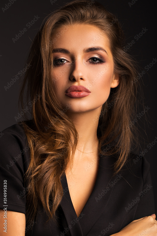 Portrait of a beautiful brunette on a gray isolated background. Luxurious girl with beautiful lips.