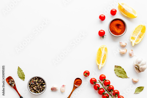 Kitchen frame with spices and food - pepper, garlic, cherry tomatoes - on white background top-down frame copy space