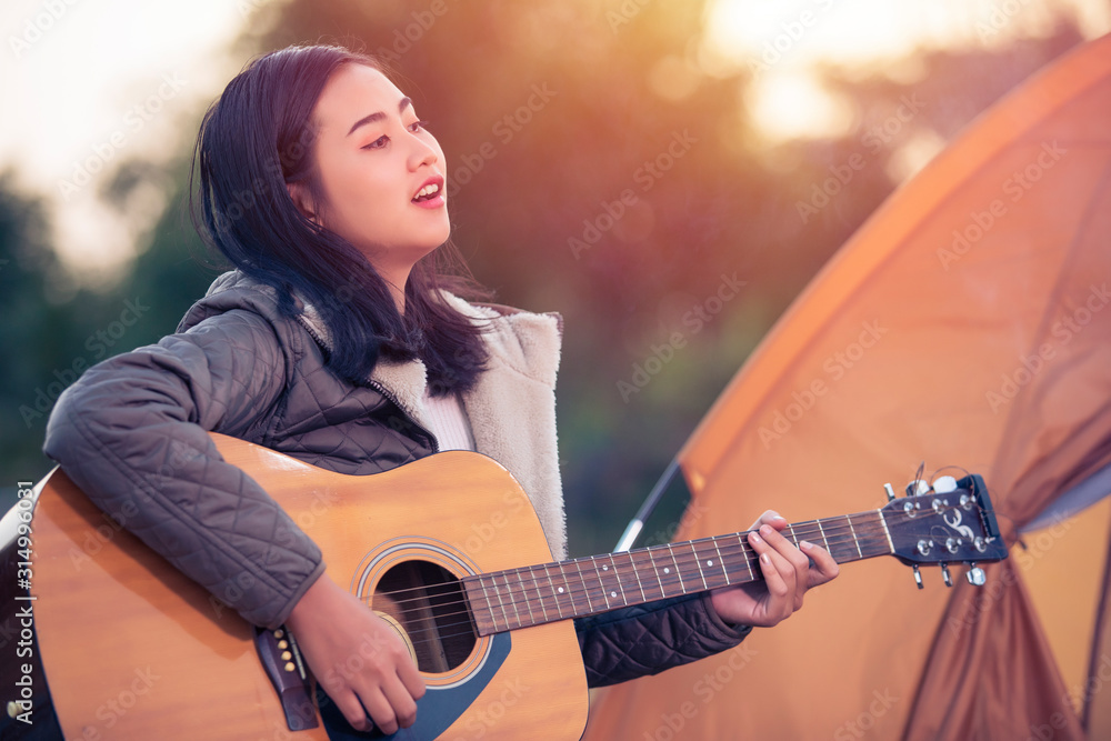 Beautiful female tourists playing guitar in camping, women with music and rest, nature tourism