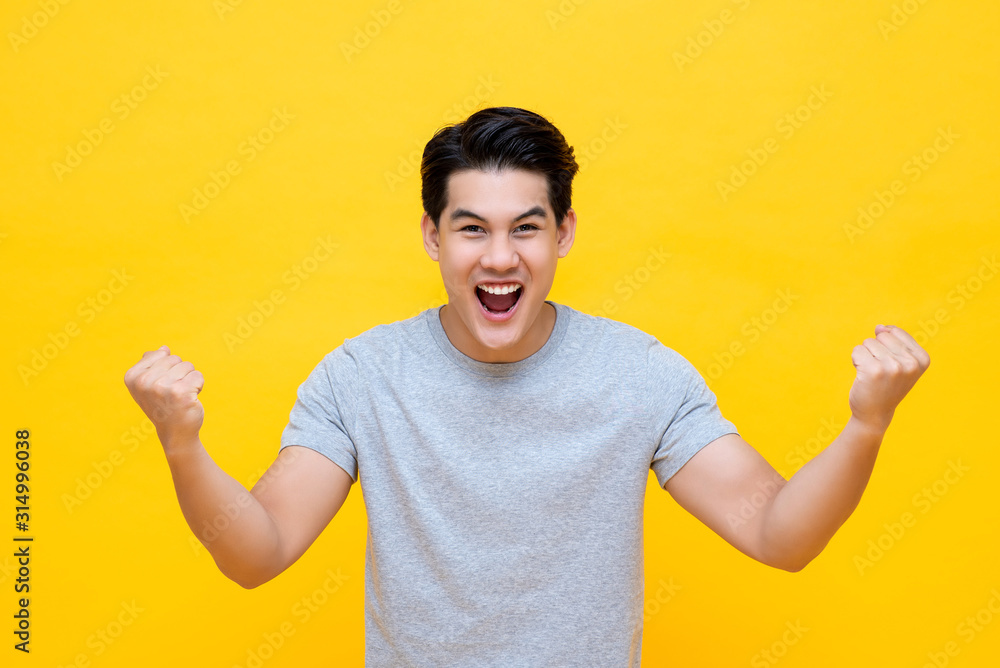Portrait of cheerful young Asian man raising his fists Portrait of cheerful young Asian man raising his fists