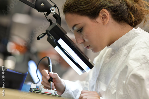 Foto Young woman apprentice working in microelectronics lab