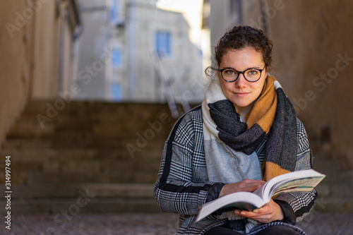 young woman sitting on stairs reading a book