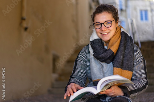 young woman sitting on stairs reading a book