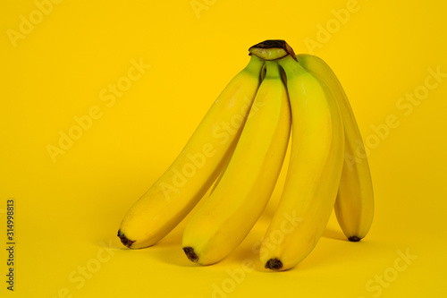 A bunch of ripe and yellow bananas shot on a bright yellow background