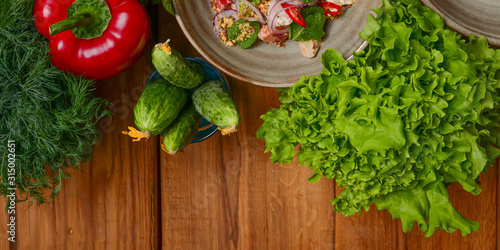 Fresh salad with rucola, cheese, cucumbers lettuce red pepper on light wooden background with free text space copy space