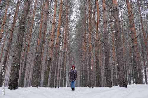 Portrait of a girl in a warm gray coat and burgundy knit scarf in the winter woods.
