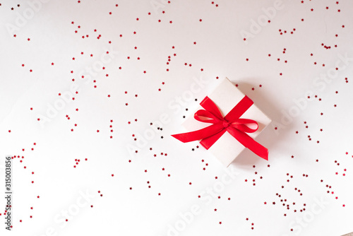 Gift with red ribbon and bow on white background background with red confetti star