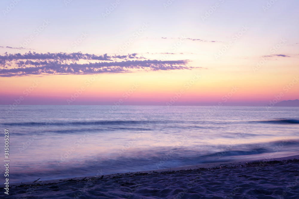 Long exposure beach landscape with purple blurred water. Pink orange horizon. Scenic seascape with sunset sky and motion blur water. Beautiful sunset sky. Long exposure beach landscape with purple blurred water. Pink orange horizon. Scenic seascape with sunset sky and motion blur water. Beautiful sunset sky.