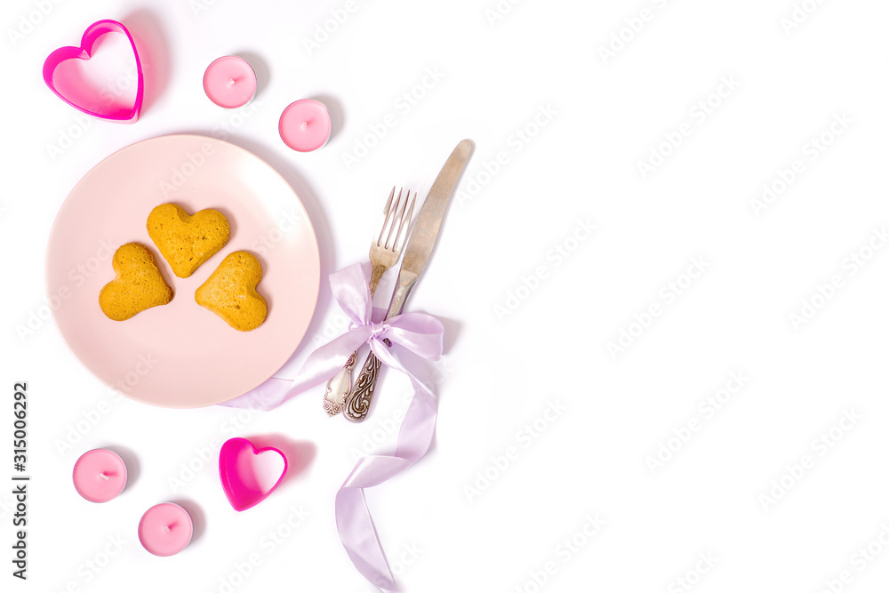 pink plate, candles, romantic dinner, heart shaped cookies, knife and fork isolated on white background, valentines day concept, flat lay